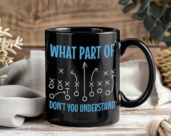 May include: Black ceramic coffee mug with the text "WHAT PART OF DON'T YOU UNDERSTAND" in light blue. The mug features a football play diagram in white.