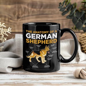 May include: Black ceramic mug featuring a diagram of a German Shepherd's anatomy. The text reads "The Anatomy of a German Shepherd" with labeled body parts like "Happy Tail" and "Golden Heart".