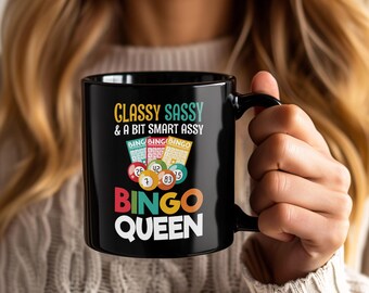 May include: Black ceramic mug with the text "Classy Sassy & A Bit Smart Assy" and "Bingo Queen" in colourful lettering. The mug features bingo balls and bingo cards. A fun gift for bingo enthusiasts.