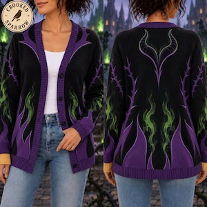 May include: A black button-up cardigan featuring a purple and green flame pattern, a V-neckline, and a large purple horn design on the back. The garment includes a circular logo in the top left corner with the text Crooked Sparrow.