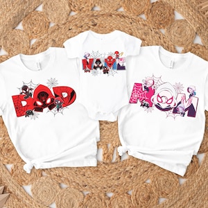 May include: White t-shirts and a onesie featuring Spider-Man-themed designs. The shirts display the words "DAD" and "MOM" in red and pink, with Spider-Man characters and spiderwebs. The onesie says "BABY" with Spider-Man characters.