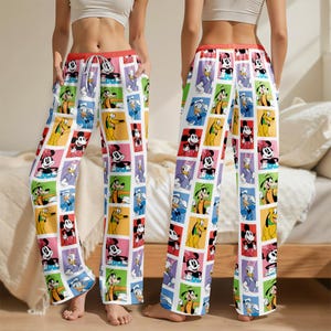 May include: Colorful pajama pants featuring a repeating pattern of Disney characters in square frames. The pants have a white background with red, yellow, green, and purple squares. The waistband is red, and the pants have a relaxed fit.