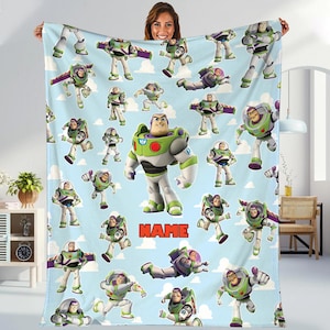 A woman is holding up a blanket featuring multiple images of the character Buzz Lightyear from the Toy Story franchise.