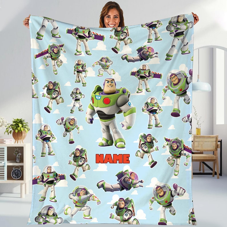 A woman is holding up a blanket featuring multiple images of the character Buzz Lightyear from the Toy Story franchise.