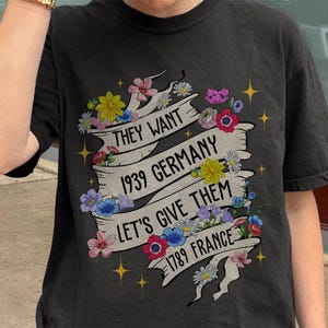 May include: Black t-shirt with a floral design and the text "They want 1939 Germany Let's give them 1789 France".