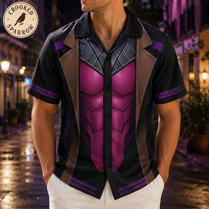 May include: A short-sleeved button-down shirt featuring a black, brown, and purple graphic print. The design includes a central purple panel with a segmented, armor-like pattern, framed by brown lapel-style graphics and black sleeves with purple stripes.