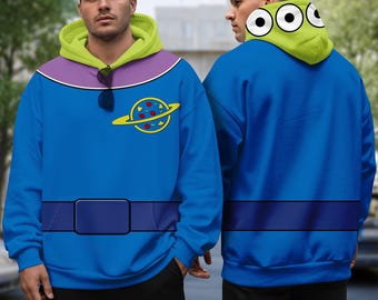 May include: A blue hoodie with a green and purple hood, featuring a cartoon planet design on the chest. The hoodie has a dark blue belt design across the midsection. The hood has three white eyes with black pupils.