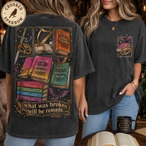 May include: A charcoal gray t-shirt featuring a large graphic on the back with illustrations of books, a sword, a harp, and a mask, along with the text 'what was broken will be remade'. A smaller matching graphic is printed on the front left chest.