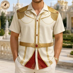 May include: A short-sleeved cream button-down shirt featuring gold epaulets with fringe, gold embroidery, and a central gold belt-like detail with a red gemstone. The shirt has a red patterned panel at the bottom and red gemstone buttons.