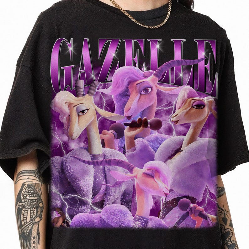 A person wearing a black t-shirt with a graphic design featuring purple and pink cartoon-like characters holding microphones and performing on a stage.