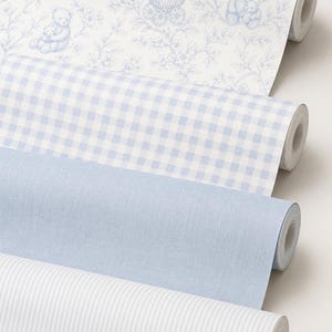 May include: Four rolls of wallpaper in various patterns. The top roll features a blue and white floral design with teddy bears and a baby carriage. Below are rolls with a blue gingham check, solid blue, and white stripes.