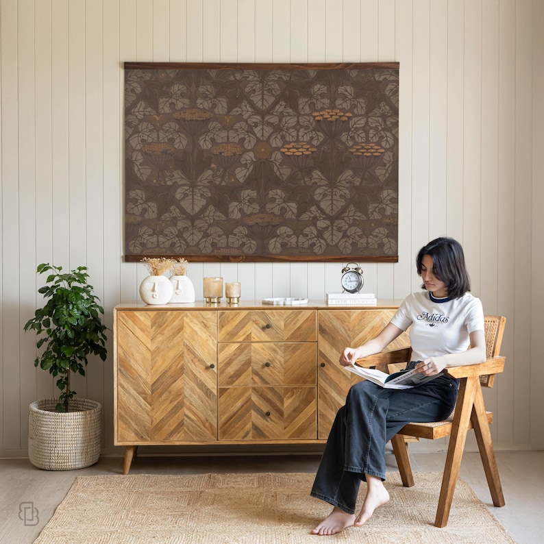 K&ouml;nnte beinhalten: Wohnzimmer mit einem Holzschrank mit Fischgr&auml;tmuster, einem gro&szlig;en gerahmten Kunstwerk mit braunem Blumendesign und einer Frau, die auf einem Holzstuhl sitzt. Eine Topfpflanze und ein gewebter Teppich vervollst&auml;ndigen die Einrichtung.