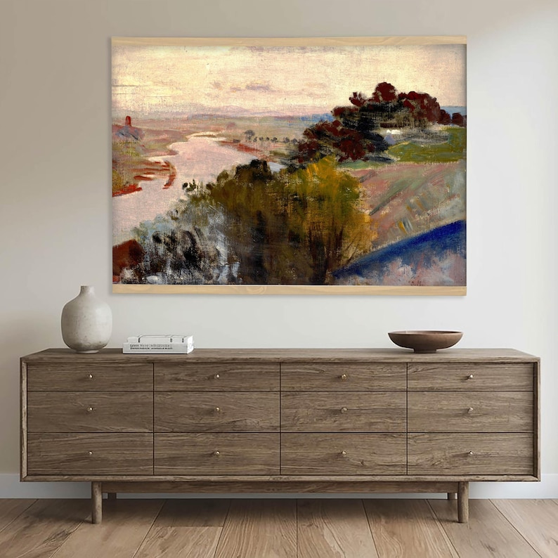 May include: A rectangular landscape painting in a light wood frame depicting a river winding through a valley with dark green and yellow trees in the foreground, rolling hills in the distance, and a pale, overcast sky above the horizon.