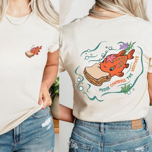 May include: A white t-shirt with a cartoon illustration of a fish eating a peanut butter and jelly sandwich. The text "Pudge Controls the Weather" is printed on the shirt.
