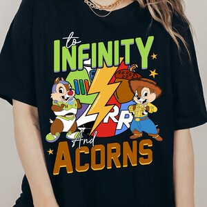 May include: Black t-shirt featuring a graphic of Chip and Dale dressed as Buzz Lightyear and Woody from Toy Story. The text "to INFINITY and ACORNS" is printed on the shirt.