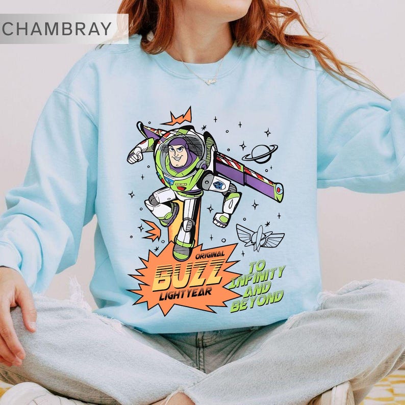 K&ouml;nnte beinhalten: Hellblaues Sweatshirt mit einer Grafik von Buzz Lightyear. Das Design enth&auml;lt den Text "Original Buzz Lightyear" und "To Infinity and Beyond". Die Cartoon-Grafik zeigt Buzz in einer dynamischen Pose. Das Sweatshirt hat einen Rundhalsausschnitt.
