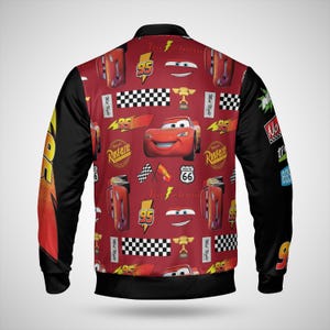 May include: A red and black bomber jacket featuring a pattern of the character Lightning McQueen from the movie Cars. The jacket has black sleeves and a red body with various graphics, including the number 95, checkered flags, and the Route 66 sign.