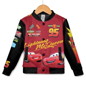 May include: Red and black Lightning McQueen bomber jacket. The jacket features the number 95, the words "Lightning McQueen", and images of the character. The sleeves are black with the number 5. The jacket has a button-up front and is hanging on a wooden hanger.