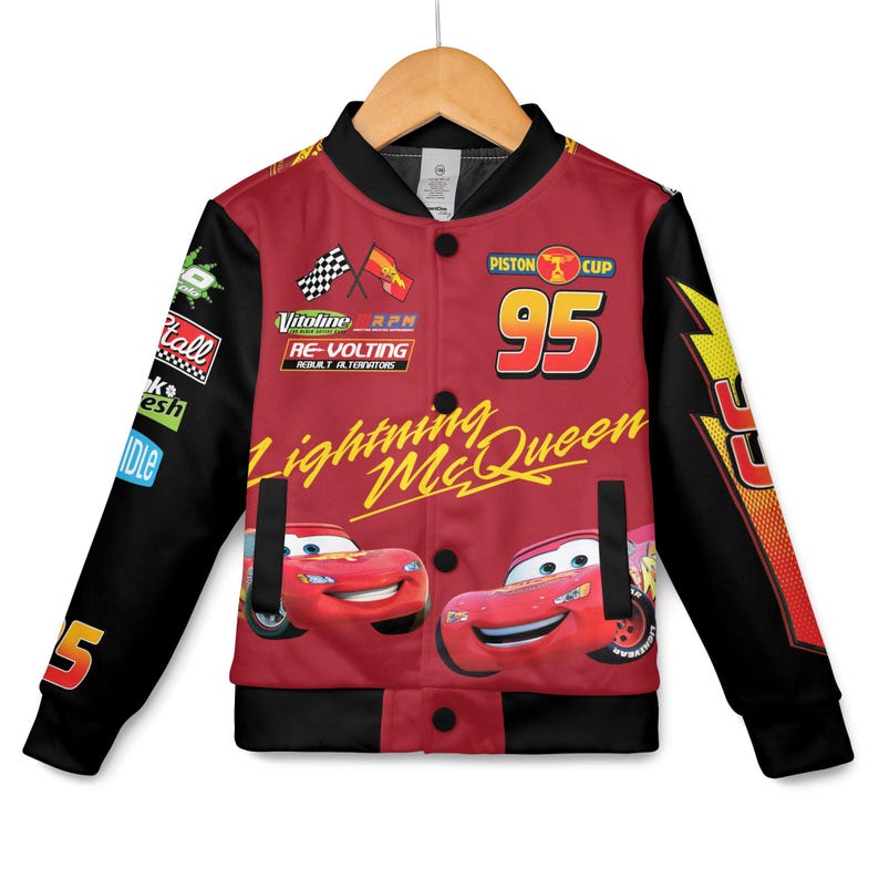 May include: Red and black Lightning McQueen bomber jacket. The jacket features the number 95, the words "Lightning McQueen", and images of the character. The sleeves are black with the number 5. The jacket has a button-up front and is hanging on a wooden hanger.
