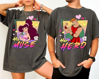 May include: A pair of gray t-shirts with a retro design featuring cartoon characters from the movie Hercules. The shirt on the left has a cartoon image of Megara with the text "His Muse". The shirt on the right has a cartoon image of Hercules with the text "Her Hero".