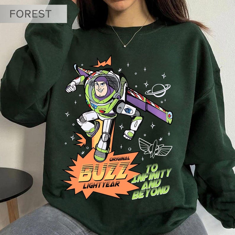K&ouml;nnte beinhalten: Dunkelgr&uuml;nes Sweatshirt mit einem Buzz Lightyear-Motiv. Das Design zeigt Buzz in Aktion, mit den Worten "Original Buzz Lightyear" und "To Infinity and Beyond". Die Grafik ist im Cartoon-Stil gehalten, mit Weltraum-Elementen.