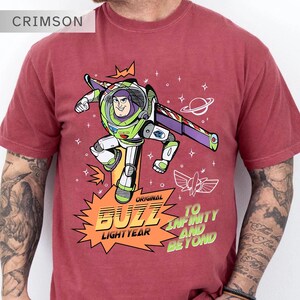 K&ouml;nnte beinhalten: Karmesinrotes T-Shirt mit einem Buzz Lightyear-Motiv. Das Design zeigt Buzz in einer dynamischen Pose, mit den Worten "Original Buzz Lightyear" und "To Infinity and Beyond". Das T-Shirt hat kurze &Auml;rmel.