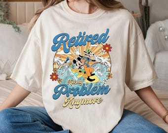 May include: A white t-shirt with a cartoon image of Mickey Mouse and Goofy surfing. The text on the shirt reads "Retired Not My Problem Anymore".