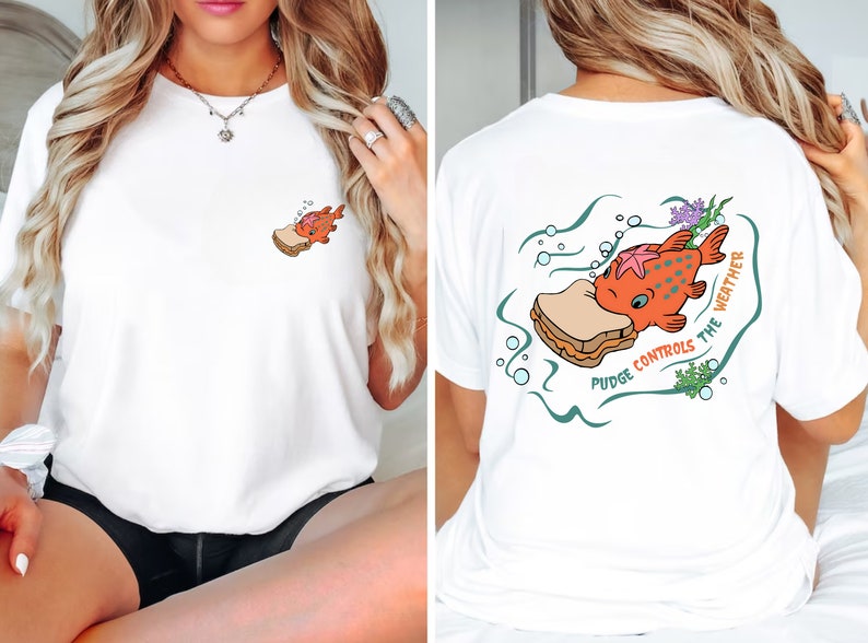 May include: White t-shirt with a cartoon fish eating a peanut butter and jelly sandwich. The text on the shirt reads "Pudge Controls the Weather".
