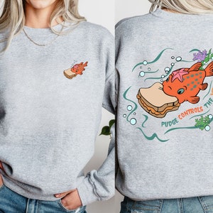 May include: Gray sweatshirt with a cartoon fish eating a peanut butter and jelly sandwich. The text on the back reads "Pudge Controls The Weather".