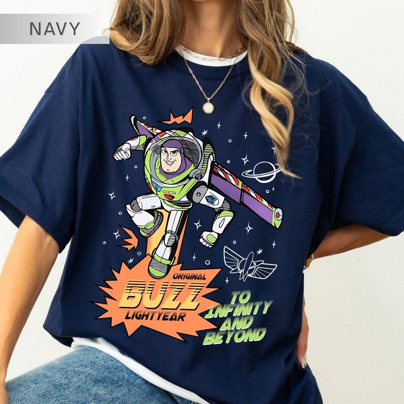 K&ouml;nnte beinhalten: Marineblaues T-Shirt mit einem Aufdruck von Buzz Lightyear aus Toy Story. Das Design zeigt Buzz in seinem Raumanzug, die Worte "Original Buzz Lightyear" und "To Infinity and Beyond". Das Shirt hat einen Rundhalsausschnitt und kurze &Auml;rmel.