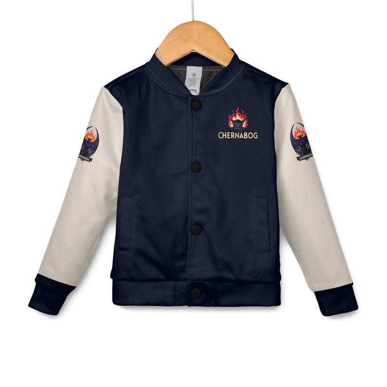 May include: A navy blue and cream-colored bomber jacket with black buttons. The jacket features the word "Chernabog" above a fiery graphic on the chest. The sleeves have a patch with a similar design. The jacket is hanging on a wooden hanger.