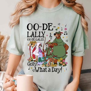 May include: A light green t-shirt with a graphic print of characters from the animated film Robin Hood. The text on the shirt reads "OO-DE-LALLY OO-DE-LALLY. Golly. What a Day!"