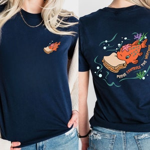 May include: A navy blue t-shirt with a graphic of a fish eating a peanut butter and jelly sandwich. The text on the shirt reads "Pudge Controls the Weather".