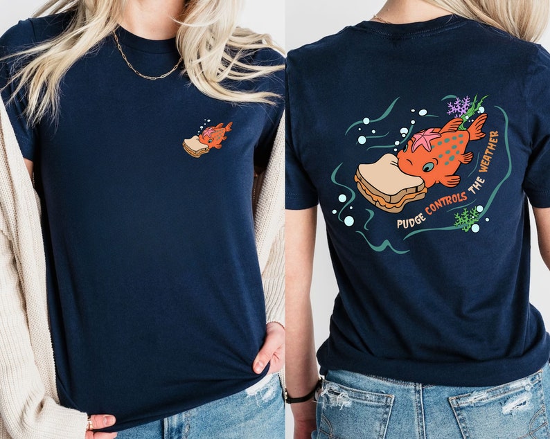 May include: A navy blue t-shirt with a graphic of a fish eating a peanut butter and jelly sandwich. The text on the shirt reads "Pudge Controls the Weather".