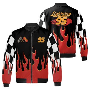 Pu&ograve; includere: Giacca bomber nera con un design a fiamme rosse e gialle. La giacca presenta un motivo a scacchi sulle maniche e il numero "95" in oro. Il retro della giacca mostra il testo "Lightning McQueen" e fiamme.