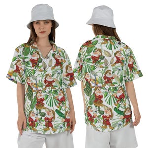 Könnte beinhalten: Weißes Hemd mit Knöpfen und einem farbenfrohen Aufdruck der Figur Grumpy aus Schneewittchen und den sieben Zwergen, umgeben von grünen tropischen Blättern und Blumen. Das Hemd hat kurze Ärmel und einen klassischen Kragen.