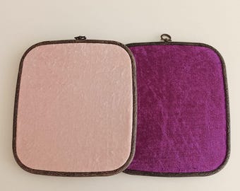 May include: Two square display boards with rounded corners and dark wood-textured frames. One board is covered in light pink velvet fabric, and the other is covered in deep purple velvet fabric. Each board features a small metal hanging loop.