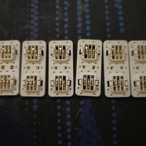 May include: Six white rectangular circuit boards with gold-coloured contacts. The boards have multiple rows of small, square holes.