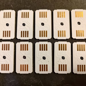 May include: Ten white rectangular circuit boards with gold-coloured connectors and a black dot in the centre.