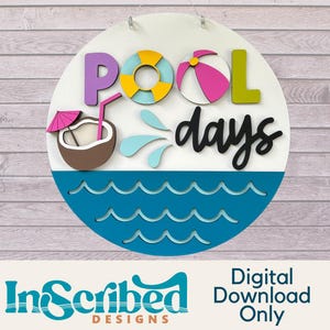 Pode incluir: Uma placa redonda de madeira com as palavras "POOL days" em letras 3D coloridas. A placa apresenta uma boia de piscina, uma bola de praia e uma bebida de coco. A metade inferior é azul com recortes de ondas. A placa é branca com fundo de madeira.