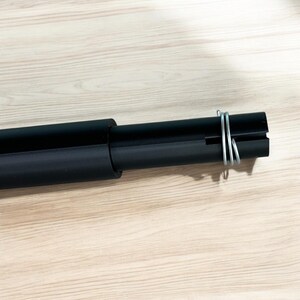 May include: A black telescopic pole with a silver wire wrapped around the end.