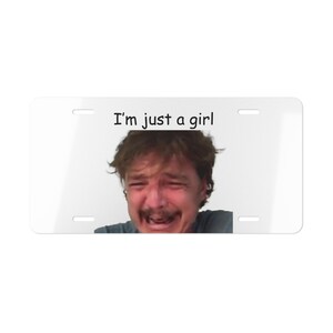 May include: A white number plate with the text "I'm just a girl" printed in black. A man with brown hair is crying and looking at the camera.