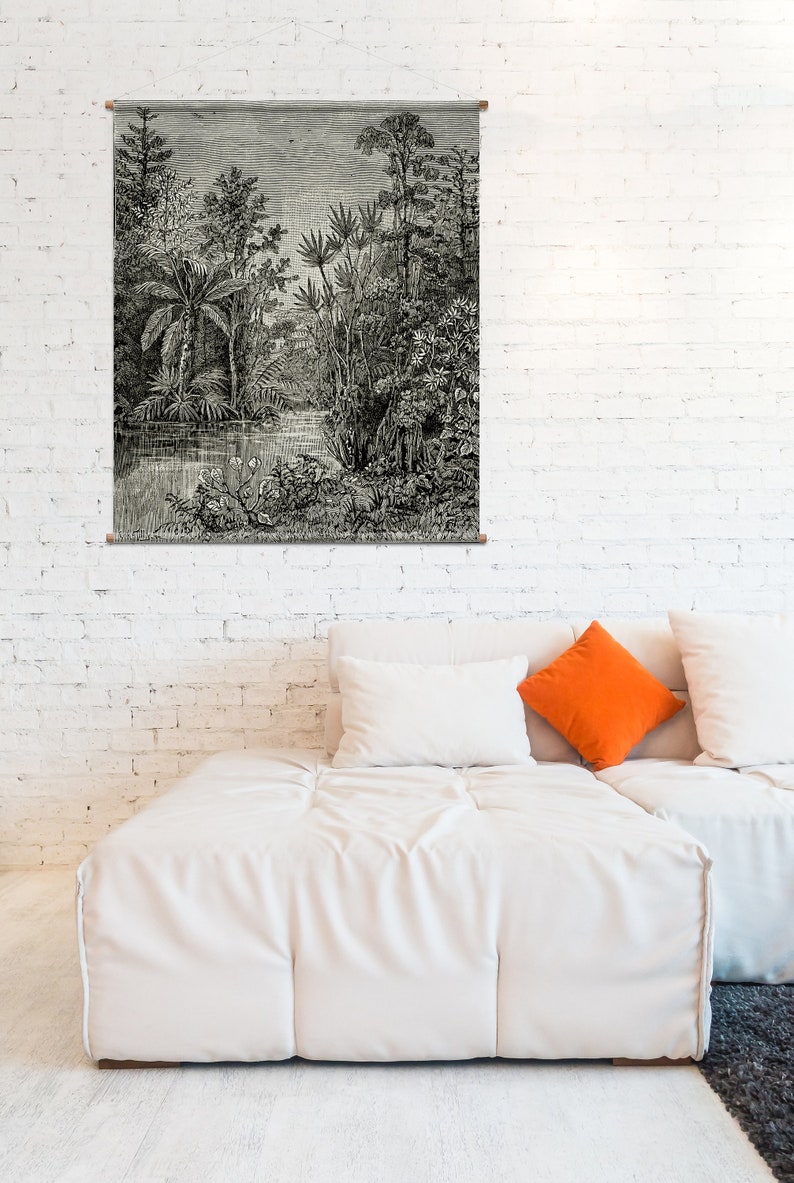 May include: A black and white illustration of a lush jungle scene with tall trees, ferns, and a small stream. The illustration is framed and hanging on a white brick wall above a white couch with orange and white pillows.