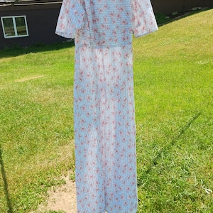 May include: A white maxi dress with a pink floral pattern. The dress has short sleeves and a V-neckline.