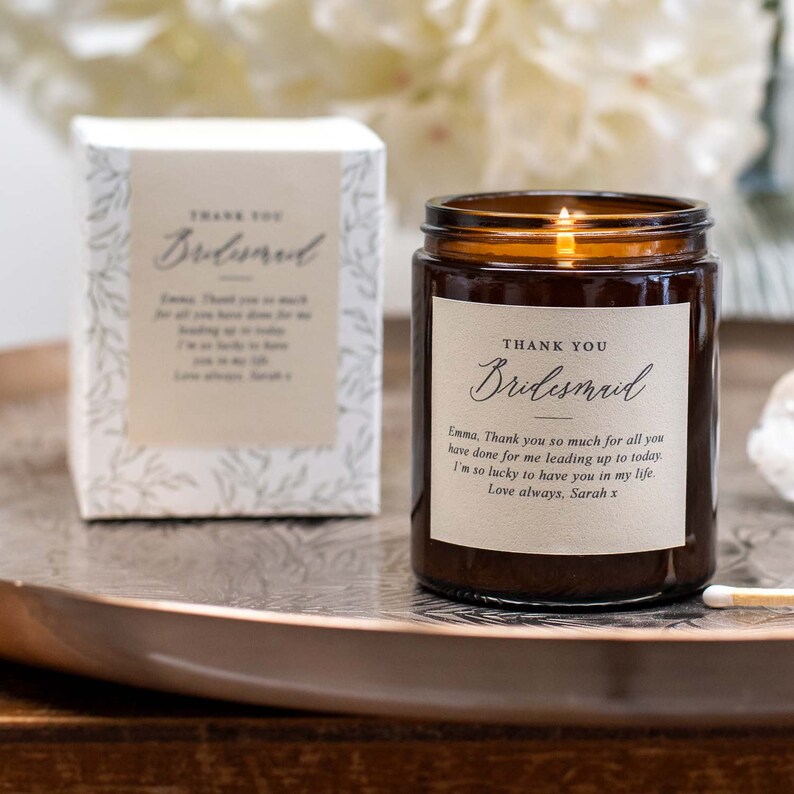 May include: A brown glass candle with a white label that says "Thank You Bridesmaid". The label also includes a personalized message: "Emma, Thank you so much for all you have done for me leading up to today. I'm so lucky to have you in my life. Love always, Sarah x".