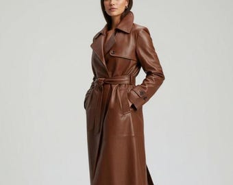 May include: A long, brown leather trench coat with a belted waist and a classic collar. The coat features long sleeves, pockets, and a knee-length design. The coat is made of a smooth, shiny leather material.