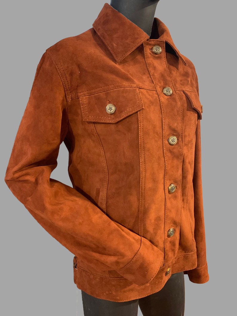 May include: A brown suede jacket with a button-up front and two flap pockets. The jacket has a classic denim style.