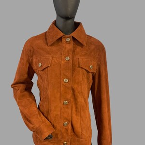 May include: A brown suede jacket with a button-up front and two flap pockets.