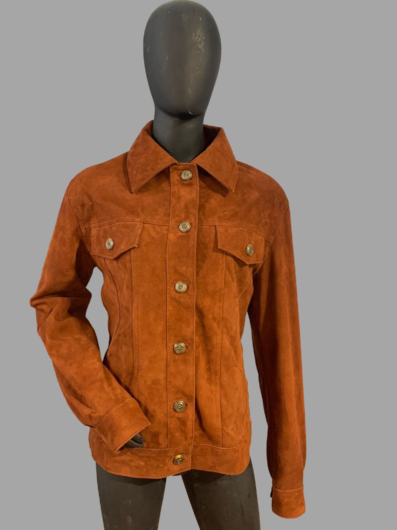 May include: A brown suede jacket with a button-up front and two flap pockets.