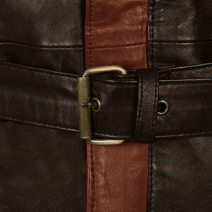 May include: A brown leather jacket with a brown leather belt and a brown leather buckle. The jacket has a vertical stripe of a lighter brown leather down the front.